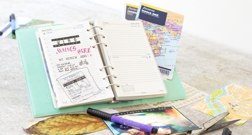 Offener Planer mit Kinoeintrag und Weltkarte im Hintergrund