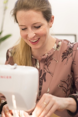 Frau näht SnapPap-Tasche mit Nähmaschine und lächelt dabei