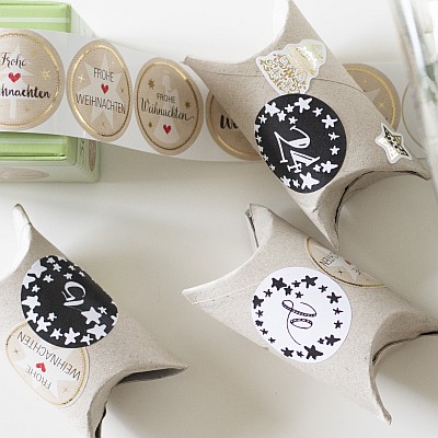 Design-Aufkleber von Avery Zweckform mit Nummern und "Frohe Weihnachten" sind auf diverse Klopapierrollen geklebt.