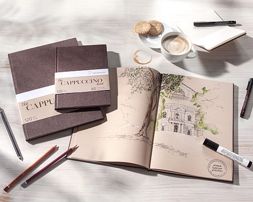 Aufgeschlagenes Skizzenbuch mit Zeichnung eines Gebäudes, 2 geschlossen Skizzenbücher und Stifte daneben