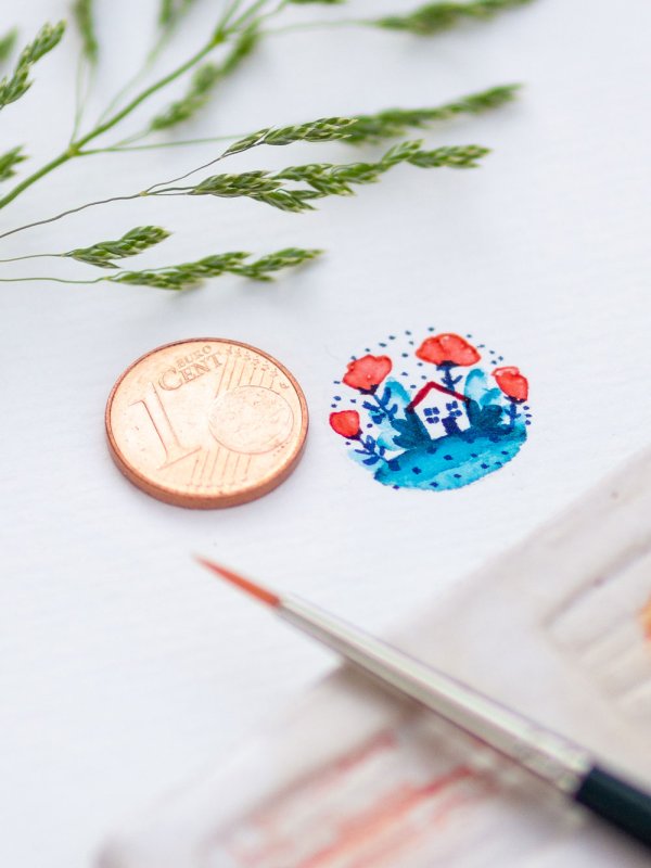 Mini-Aquarellhaus mit Blumen in der Größe eines 1-Cent Stücks neben 1-Cent-Münze und Pinsel