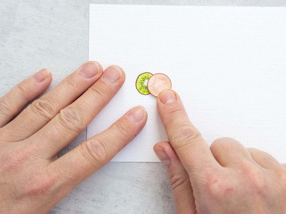 1-Cent-Münze liegt neben Kiwi-Malerei zum Größenvergleich