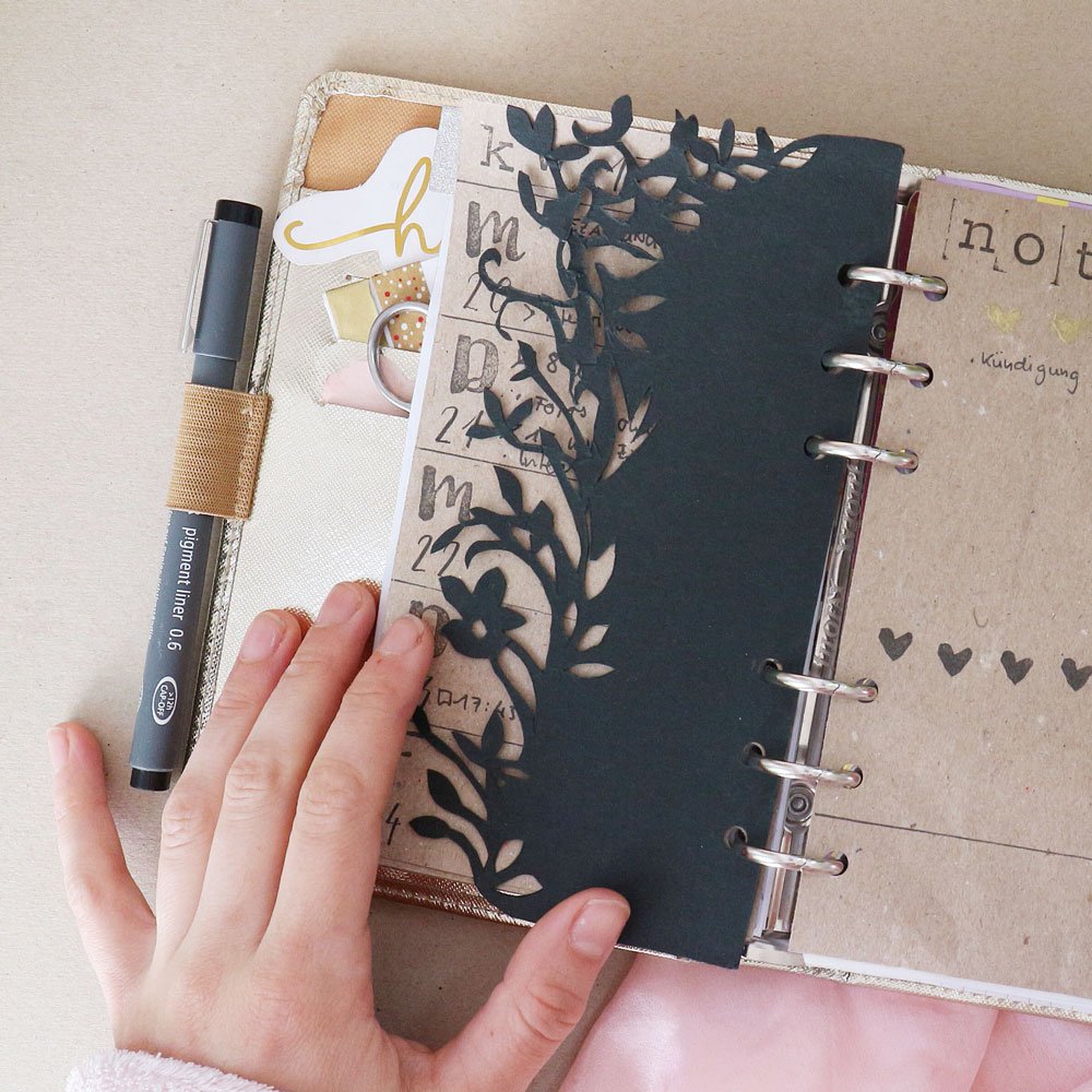 Ein aufgeschlagener Filofax-Kalender zeigt eine gestanzte Einlage mit Blumenmotiv. 