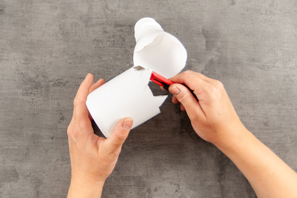 Eine weiße PEF-Flasche wird mit einem Cutter auseinander geschnitten