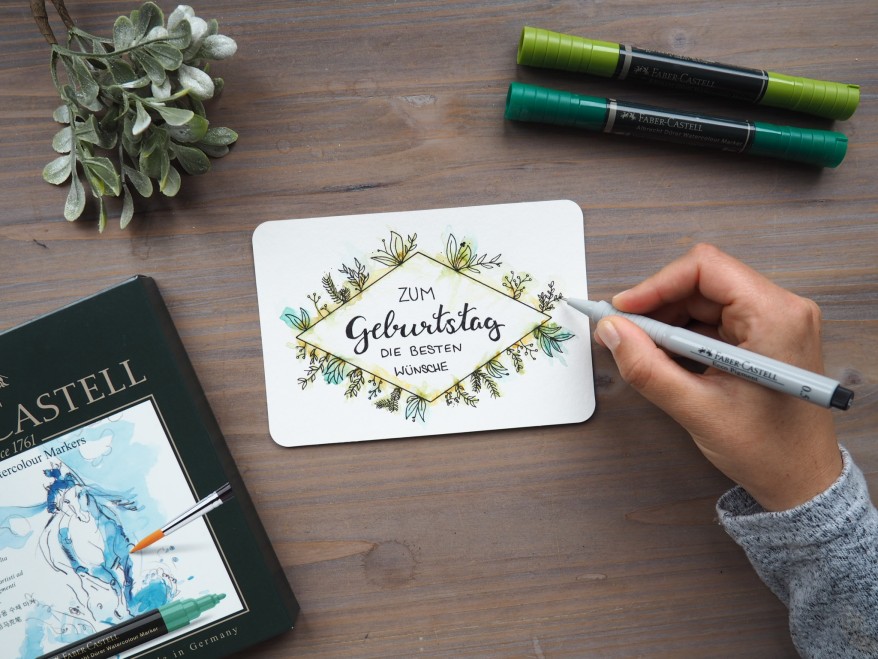 Eine Hand koloriert eine florale Geburtstagskarte mit einem Faber-Castell Stiften.