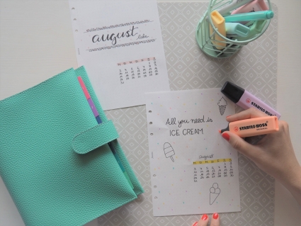 Hand markiert Eis-Motiv-Kalenderblatt mit Text „All you need is Ice Cream“, daneben ein geschlossen Planner von Filofax.