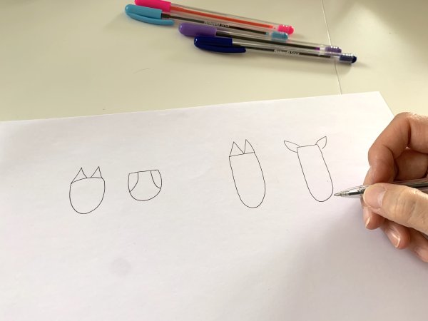 Jemand zeichnet Umrisse mit Kugelschreiber auf ein Papier