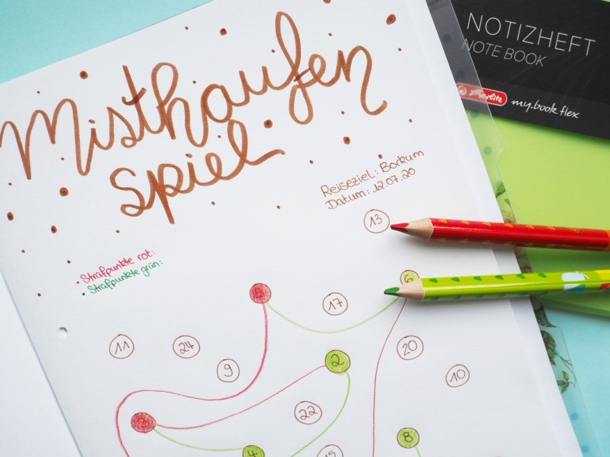 Handgezeichnetes „Misthaufen-Spiel“ auf Papier mit roten und grünen Buntstiften.