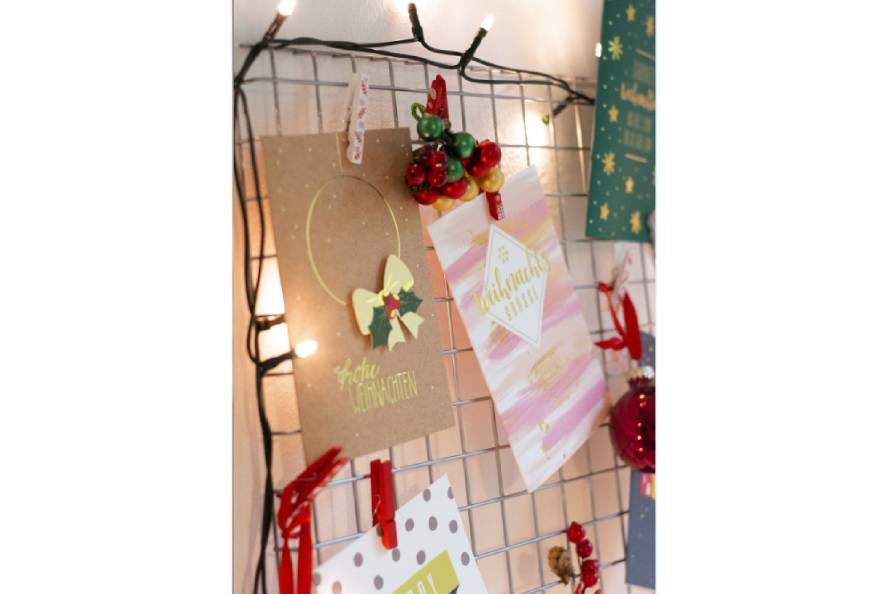 Weihnachtskarten, Lichterkette und Weihnachtsschmuck an Gitter