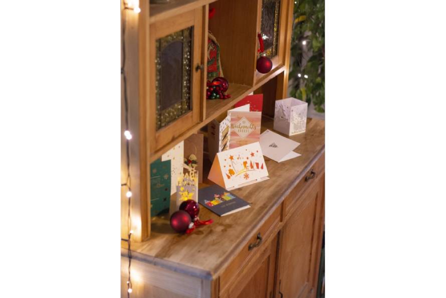 Weihnachtskarten mit Weihnachtskugeln auf einer Kommode, festlich arrangiert