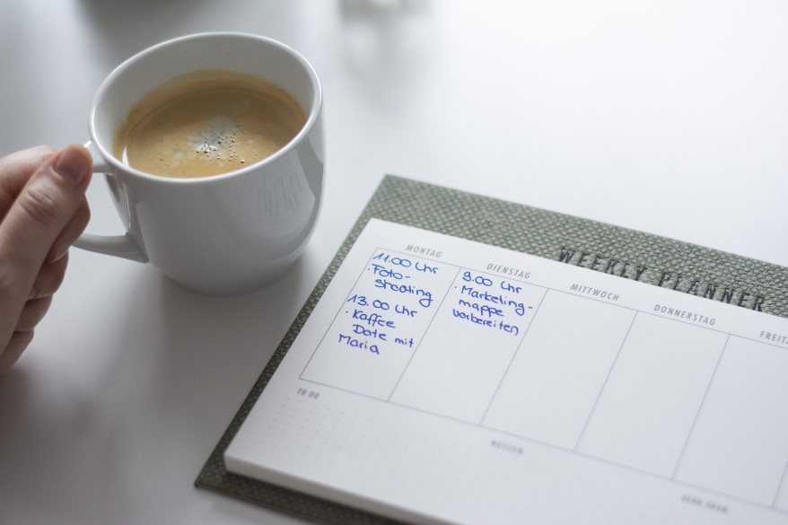 Nahaufnahme vom weekly planner aus der S.O.H.O.-Serie von Rössler. Daneben hält eine Hand eine Kaffeetasse.