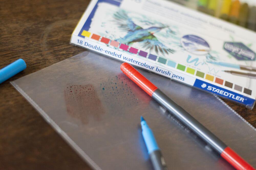 Auf einer Dokumentenhülle sind zwei Farbflecke in blau und rot mit Brush Pens von Staedtler aufgemalt.