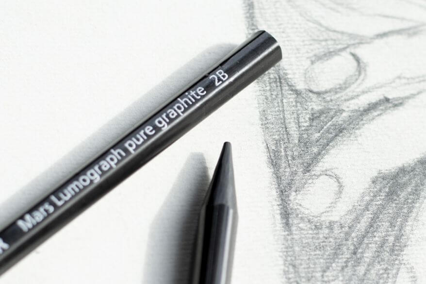 Nahaufnahme eine Vollgraphitstifts der Marke Staedtler. Im Anschnitt zu sehen ist die Bleistiftzeichnung einer Hand.