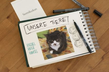 Ein Trostalbum für Kindergartenkinder: Ein Foto von einer Katze ist in ein Fotoalbum Mini Mucho von Semikolon eingeklebt. Darüber steht geschrieben "Unsere Tiere" und "Kuschelkater Ramses".