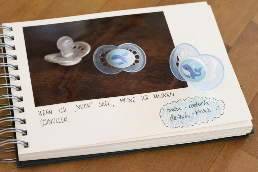 Ein Trostalbum für Kindergartenkinder: Ein Foto mit Schnullern ist in ein Fotoalbum Mini Mucho von Semikolon eingeklebt, darunter steht geschrieben "Wenn ich Nuck sage, meine ich meinen Schnuller."