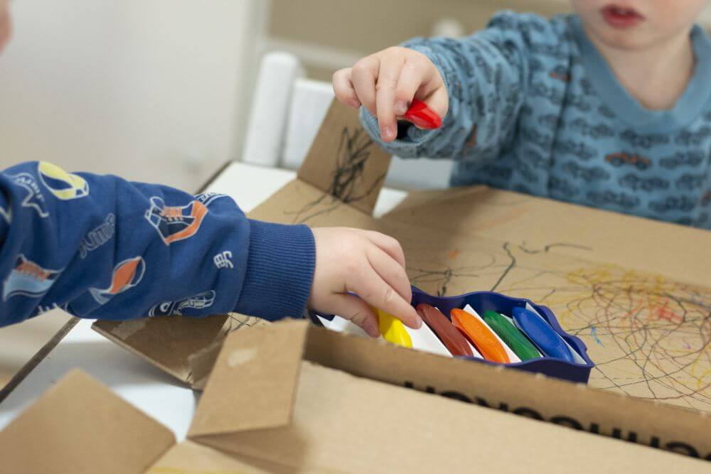 Zwei Kinder greifen in eine Stiftebox der Kreativfabrik von Pelikan.