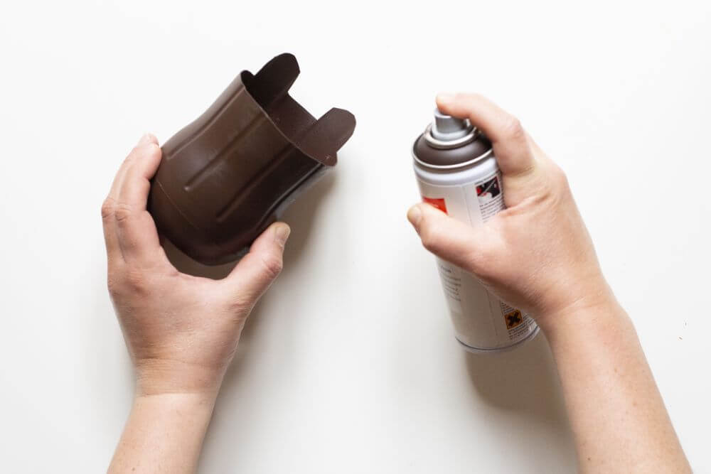 Der Boden einer PET-Flasche wird mit brauner Sprühfarbe von edding besprüht.