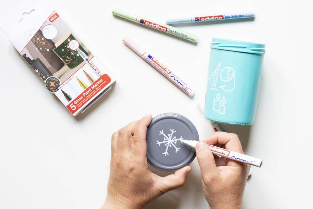 Anleitung Upcycling-Adventskalender aus Glas basteln, Schritt 3: Besprühte Einmachgläser mit kleinen, weihnachtlichen Zeichnungen versehen.