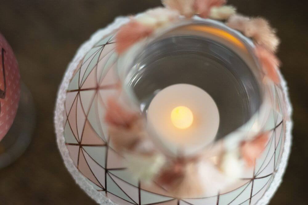 Blick von oben in ein Weinglas, mit Teelicht und Lampenschirm verziert.