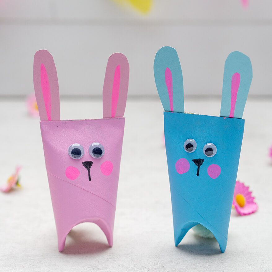 Ein rosafarbener und ein hellblauer Osterhase stehen vor einem weißen Hintergrund. Sie sind aus Klorollen gebastelt, die Wackelaugen sind von Heyda. Drumherum liegen künstliche Streublumen von Knorr-Prandell. Fotos: Johanna Rundel