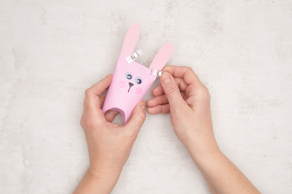 Zwei Hasenohren werden in die flachgedrückte Oberkante einer Rosa bemalten Klorolle mit Hasengesicht eingeklebt und mit kleinen Klammern fixieren. Fotos: Johanna Rundel