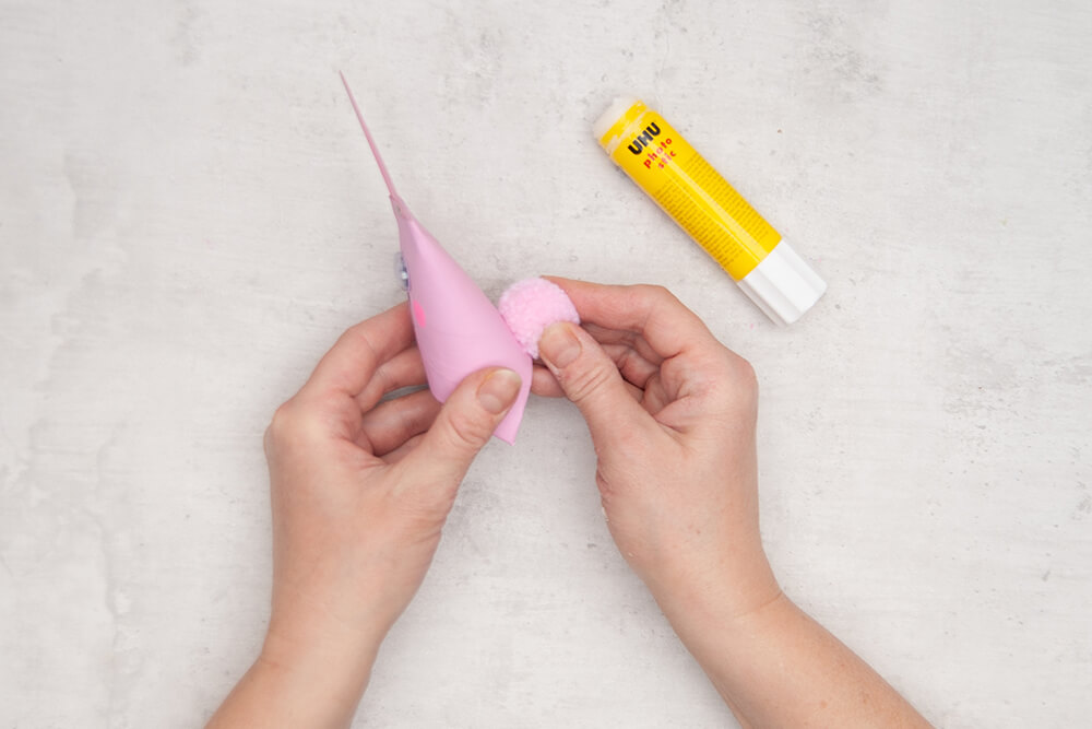 Eine Bommel wird als Hasenschwänzchen auf die Rückseite einer gebastelten, rosafarbenen Hasenschachtel aus einer Klopapierrolle geklebt. Fotos: Johanna Rundel