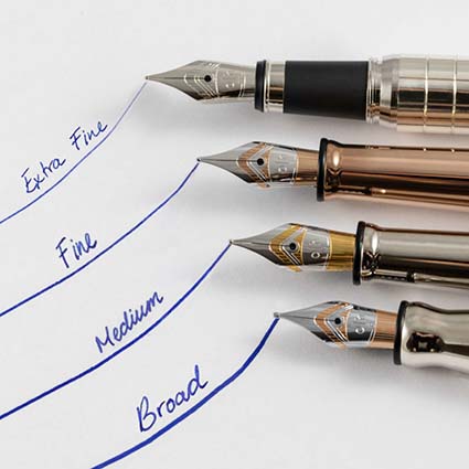 Im Anschnitt sind vier Füller mit verschiedenen Federbreiten zu sehen. Mit diesen wurde auf ein weißes Blatt Papier die Worte "Extra Fine, Fine, Medium und Broad" geschrieben.