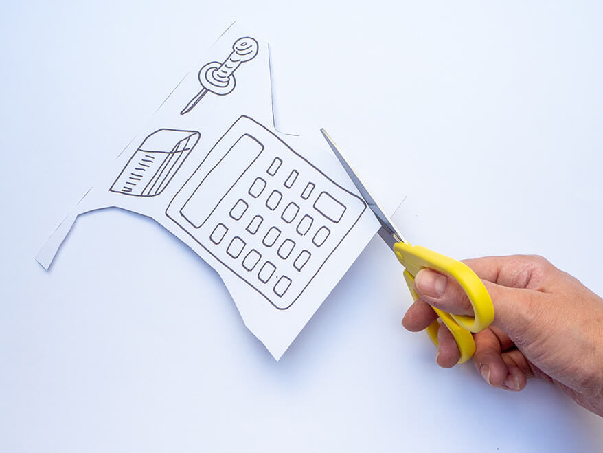 Jemand möchte Foto-Props für die Einschulung basteln und schneidet dafür eine gezeichnete Papier-Vorlage in Form eines Taschenrechners aus. Foto: Johanna Rundel