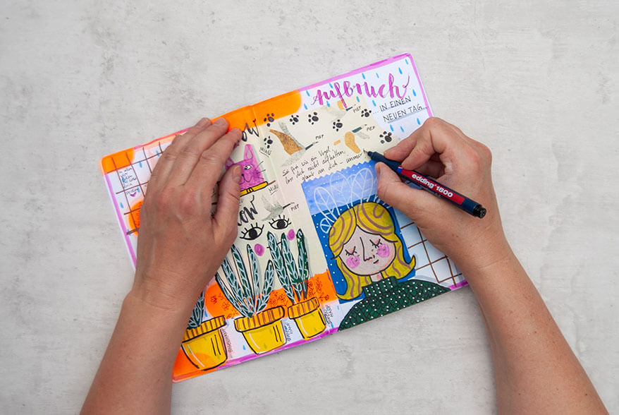 Jemand schreibt mit einem schwarzen Pigment-Fineliner von Edding Text in ein Art Journal im Mixed-Media-Stil. Außerdem zu sehen sind eine rosa Katze, mehrere Topfpflanzen, eine blonde Frau und Augen. Foto: Johanna Rundel