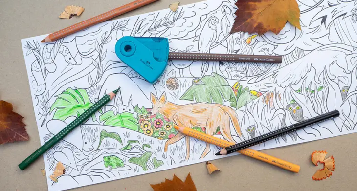 Auf einem Kraftpapier liegt ein großes Ausmalbild mit Waldmotiv. Einige Teile davon sind schon ausgemalt, beispielsweise ein Fuchs. Auf und um das Bild sind Herbstblätter, Spitzer-Reste und ein Spitzer von Faber-Castell, in dem ein Stift steckt, verteilt. Foto: Johanna Rundel