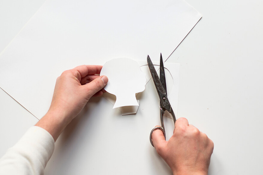 Anleitung für einen Do-it-yourself-Scherenschnitt. Schritt 3: Das Profil des Kindes wird auf dem cremeweißen Tonpapier ein zweites Mal ausgeschnitten.