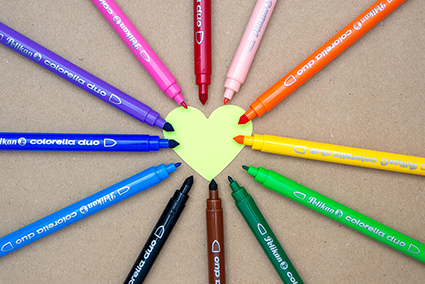 Auf einem Kraftpapier liegt ein ausgestanztes, hellgrünes Herz aus Papier. Drumherum liegen Fasermaler der Produktlinie Colorella von Pelikan im Kreis. Die Kappen der Stifte sind abgenommen und die verschieden dicken Spitzen sind zu sehen. Sie zeigen auf das Herz. Foto: Johanna Rundel