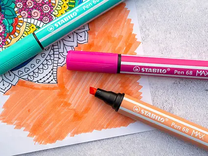 Dicke Stifte mit Keilspitze von Stabilo liegen auf einer großflächig schraffierten Fläche eines Mandalas zum Ausdrucken.