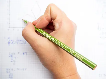 Jemand schreibt mit einem grünen Bleistift von STABILO in ein Rechenheft. Foto: Johanna Rundel