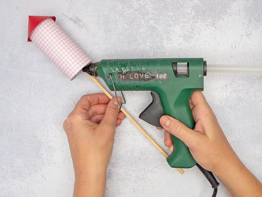 Jemand klebt einen Holzstab auf die Innenseite einer selbstgebastelten Silvesterrakete aus Papier von HEYDA. Foto: Johanna Rundel