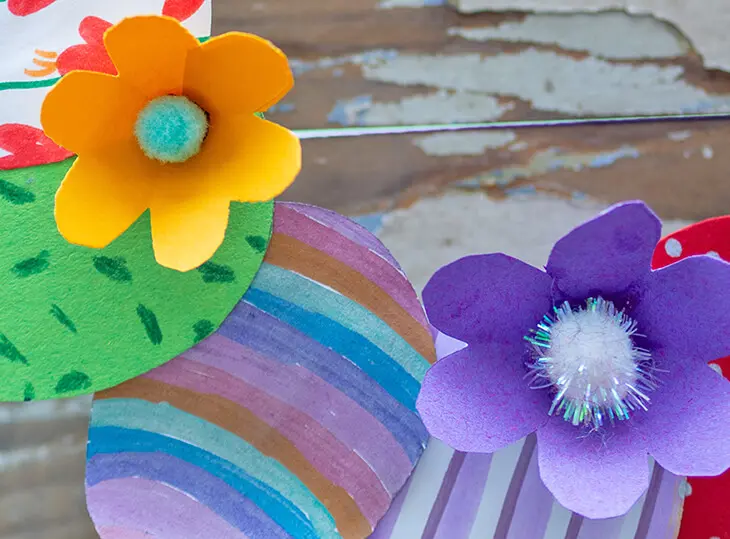 Ausschnitt eines selbstgebastelten Osterkranzes aus bunt angemalten Papiereiern mit bunten Papierblüten. Foto: Johanna Rundel