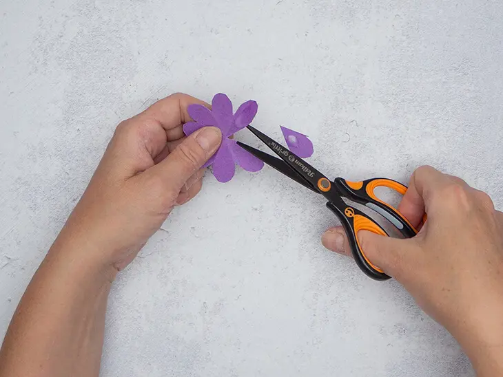 Jemand schneidet mit einer griffix-Schere von Pelikan ein Segment aus einer Papierblumen-Silhouette. Foto: Johanna Rundel