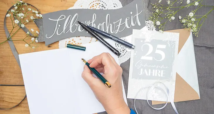 Jemand schreibt mit einem grünen Füller von Faber-Castell eine Glückwunschkarte zur Silberhochzeit. Foto: Johanna Rundel