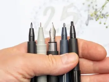 Jemand hält verschiedene Stifte von Faber-Castell mit unterschiedlichen Stiftspitzen in einer Hand vor einem unscharfen Hintergrund. Foto: Johanna Rundel