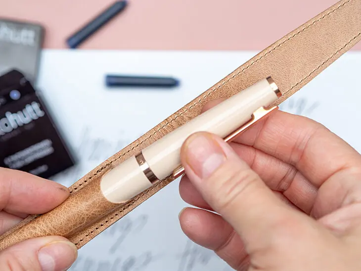 Jemand steckt einen roséfarbenen Kugelschreiber von Otto Hutt in ein passendes Etui aus Naturleder. Foto: Johanna Rundel