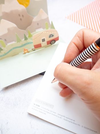 Jemand schreibt mir einem schwarz-weißen Kugelschreiber von Grafik Werkstatt einen Text in eine Karte zur Rente. Foto: Johanna Rundel