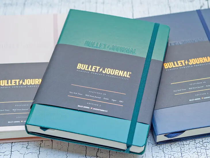 Ein grünes, ein rosa und ein dunkelblaues Bullet Journal von LEUCHTTURM1917 liegen nebeneinander. Foto: Johanna Rundel