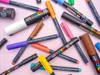 Verschiedene Kreativmarker von Faber-Castell und POSCA liegen kreuz und quer auf einem rosa Untergrund verteilt. Foto: Johanna Rundel