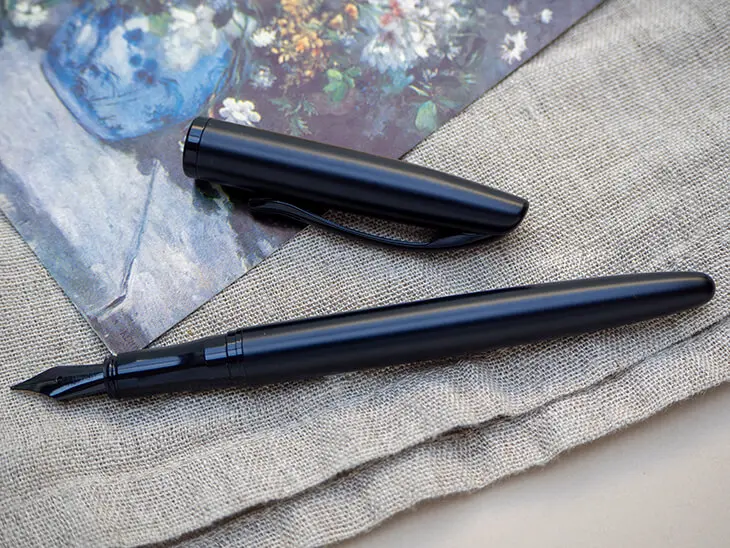 Ein schwarzer Jazz-Füller von Pelikan liegt auf einer Postkarte mit klassischem Gemälde-Motiv auf einer Leinendecke. Foto: Johanna Rundel