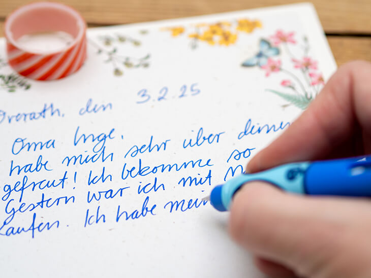 Jemand schreibt mit einem Schreiblernfüller von Pelikan einen Brief auf ein geblümtes Briefpapier. Foto: Johanna Rundel