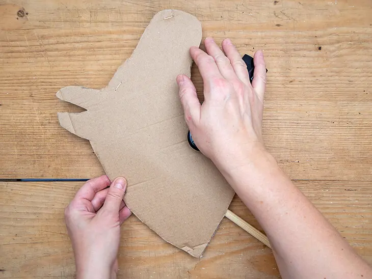 Jemand tackert zwei Pferdeköpfe aus Pappe mit einem Tacker zusammen. Foro: Johanna Rundel