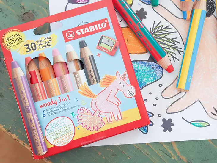 Eine Packung Woody 3in1 Buntstifte von STABILO in der Geburtstagsedition mit pupsendem Einhorn auf dem Cover liegt auf einem Ausmalbild mit Frühlingsmotiven. Foto: Johanna Rundel