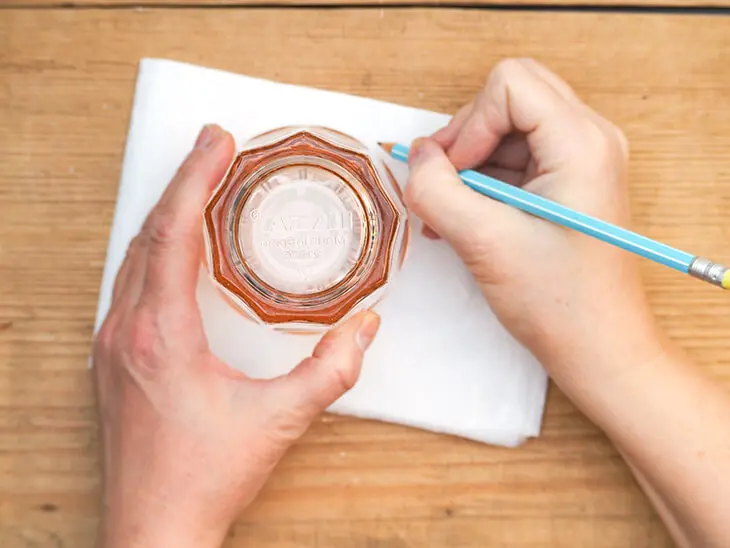 Jemand umfährt ein Wasserglas mit einem Bleistift, um einen Kreis auf einen Stapel Strohseide von HEYDA zu übertragen. Foto: Johanna Rundel