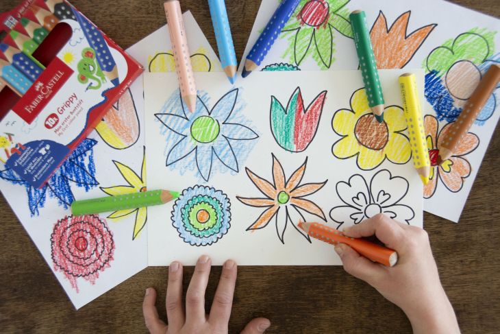 Jemand malt Blumen auf einer Vorlage mit Buntstiften von Faber-Castell aus.