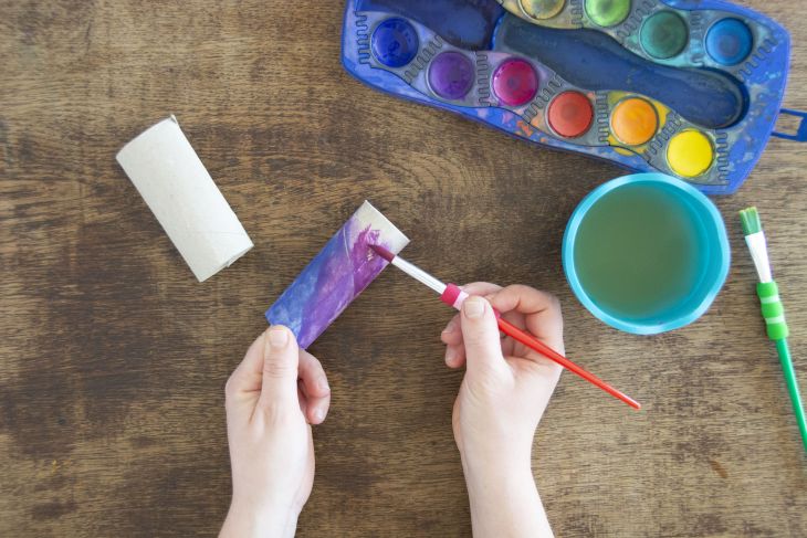 Jemand malt eine Klopapierrolle mit Wassermalfarben von Faber-Castell an.